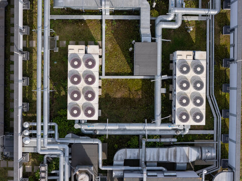 Aerial view of industrial HVAC ventilation units and metallic piping systems installed on a green rooftop in Gdansk, Poland.