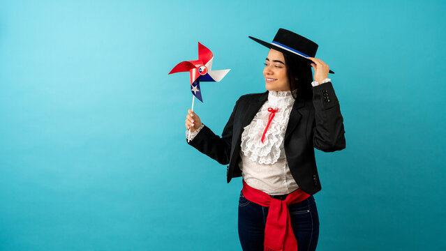 Young woman in traditional huasa costume holding a chilean flag pinwheel