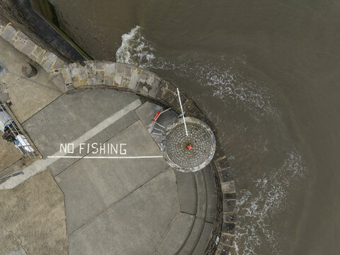 Wales, United Kingdom - 20 May 2026: Aerial view of Saundersfoot Beach featuring a concrete pier with a painted no fishing sign and a circular stone structure overlooking the sea.