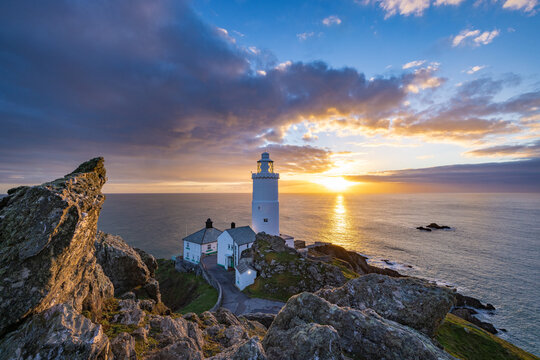 Start Point, United Kingdom - 05 January 2022: View of Start Point Lighthouse standing on rocky cliffs at sunset with the sea in the background.
