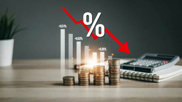 Financial concept showing stacks of coins, a decreasing bar chart, and a red downward arrow with percentage sign representing economic recession or falling interest rates