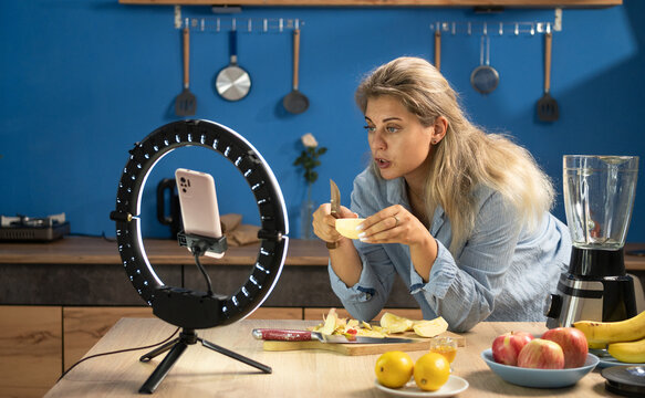 Food blogger livestreaming from kitchen using smartphone and ring light, creating videos for social media followers about healthy food, diet and proper nutrition. food blogging.