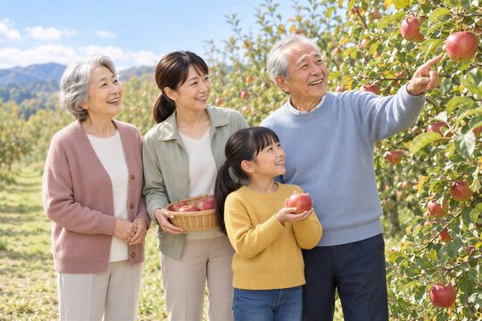 秋のりんご園で収穫体験を楽しむ祖父母と娘と孫娘