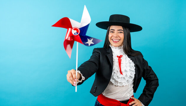 Happy woman wearing huaso attire, holding a chilean flag pinwheel