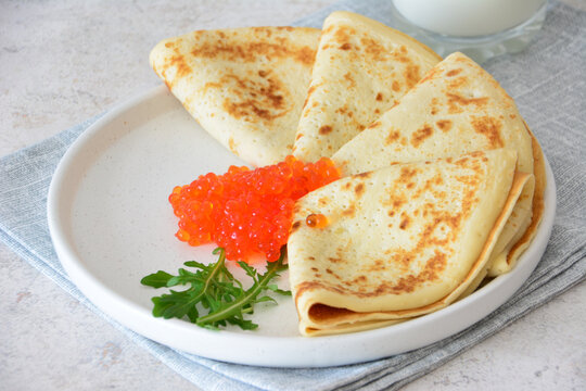 crepes with Red Caviar and Arugula on white Plate, close up