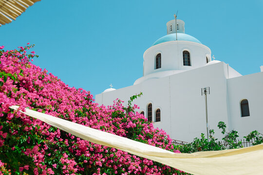 View of Santorini, Greece with blue dome churches and cliff views of houses and businesses overlooking the caldera. Famous tourism destination.