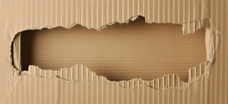 Textured brown cardboard with a large torn hole in the center torn paper ripped cardboard texture