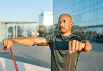 Fototapeta premium Portrait of a happy handsome black man exercising with resistance band and stretching outdoors