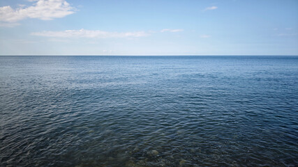 A calm ocean scene with clear blue water and a bright sky. Gentle waves create a serene atmosphere. Ideal for themes of relaxation and nature. © Sergey