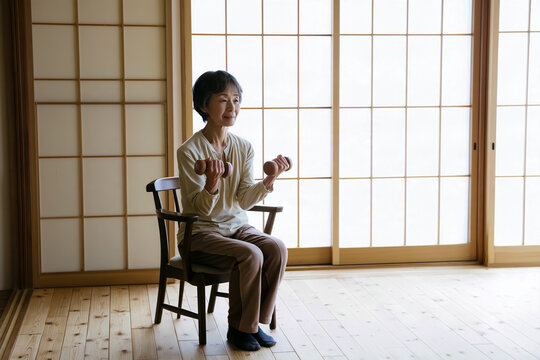 自宅でダンベルを使って筋トレをするシニア女性
