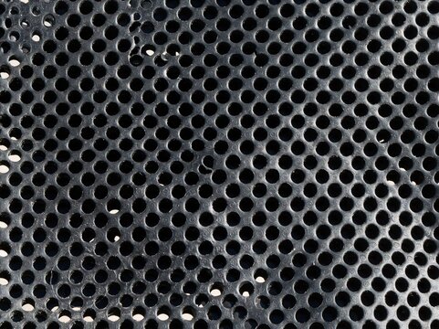 Perforated pattern mesh with a tactile industrial feel, featuring round holes in charcoal grey for background textures and design elements