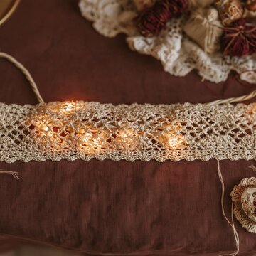 Christmas lights glowing behind a vintage lace band on a deep plum fabric, cozy and sentimental for holiday invitation and craft design