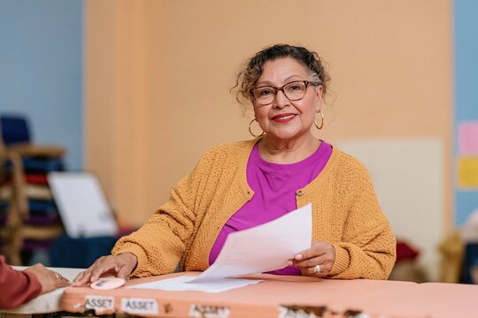 Midterm elections poll worker handing a round sticker across a worn table, featuring a natural Hispanic woman in a warm setting