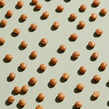 Vegetarian pulses and split peas arranged in a clean pattern on a sage green background for healthy eating and food design