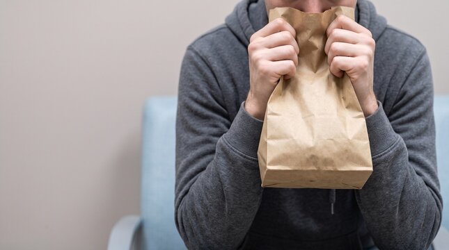 Adult person managing anxiety with paper bag breathing technique