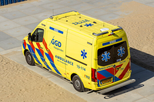 Yellow van ambulance seen from above parked on beach of The Hague coast boulevard