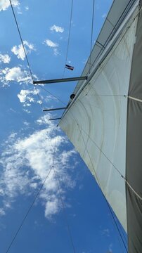 White sails filled with wind against a blue sky above a sailing yacht. Wind powered navigation and freedom at sea.