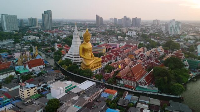 Giant golden Buddha statue and stupa at Wat Paknam Bhasicharoen with sky dusk light, panoramic aerial view