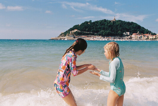 Two young girls playing in the surf at a scenic city beach.