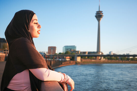 Woman in hijab gazing over river in Dusseldorf Germany