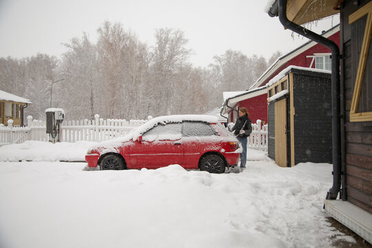 Woman clearing snow from red car