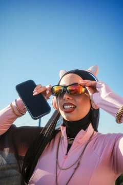 Woman with cat ear headband adjusting mirrored sunglasses