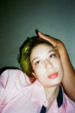Green-haired person gazing upward in pink shirt