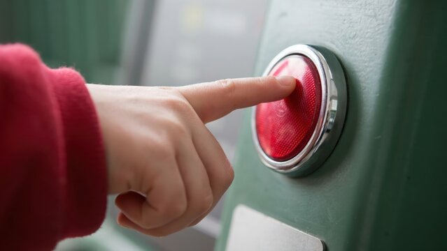 A person pushing a red button on a control panel in natural lighting. This image is ideal for concepts involving technology, action, and decision making.