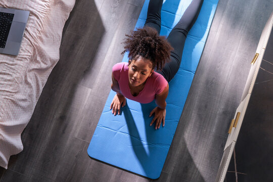 Young woman practices yoga in her home bedroom