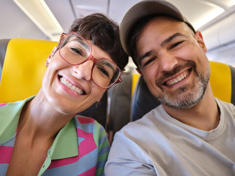 Happy couple smiling on airplane during journey