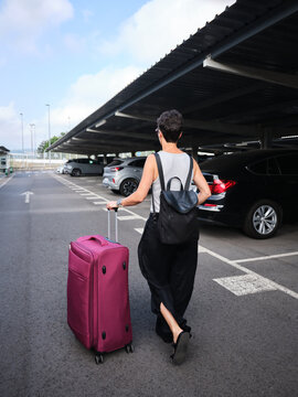 Woman walking with suitcase at airport parking lot