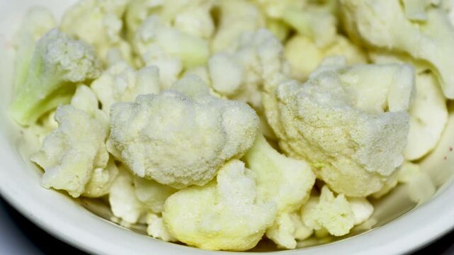 A white bowl filled with cauliflower florets on a table
