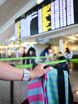 Passenger holding luggage looking at airport flight information