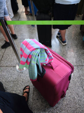 Pink suitcase waiting in airport queue for travel