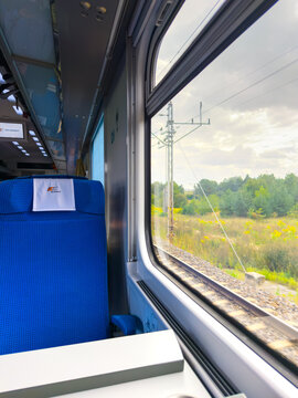 Krakow, Polska - September 22, 2026 blue passenger seat in pkp intercity train, interior view looking out window at scenic green countryside landscape, nature view during trip, 