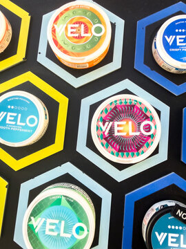Krakow, Polska - September 22, 2026: VELO nicotine pouch containers appear in a colorful overhead arrangement, showing varied circular labels and hexagonal backgrounds