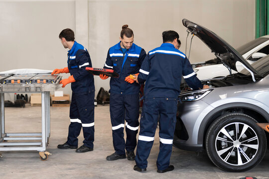 EV Mechanics. Electric vehicle battery health. Mechanics checking EV or electric vehicle battery pack. Car engine with hood open during repair. Mechanic inspects and repairs