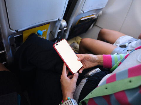 Passenger holding smartphone with blank screen on airplane