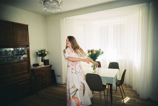 Woman Dancing in a Bright Room With Flowers and a Table