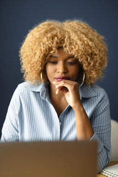 Woman Working on a Laptop and Thinking in a Modern Workspace