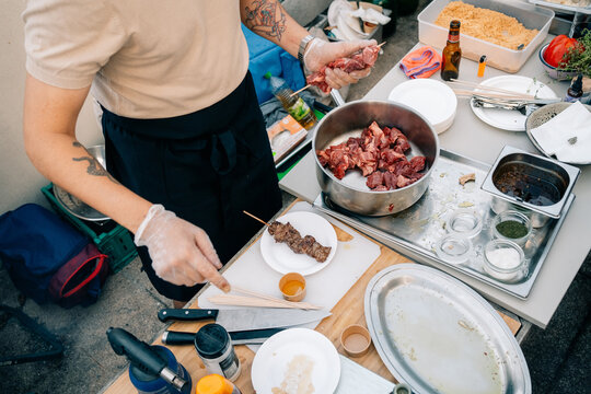 Cooking Meat and Preparing Skewers Outdoors at a Gathering