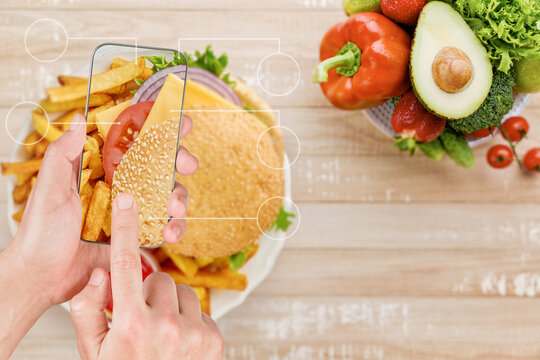 Phone scans a burger for calories beside a bowl of fresh produce
