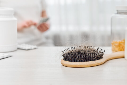 Hairbrush full of shed hair with vitamins and a phone in the background