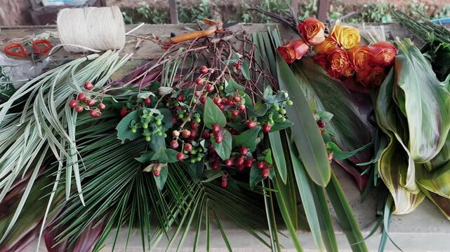 assortment of fresh cut flowers and tropical foliage on a wooden table