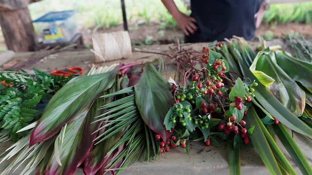 florists arranging fresh flowers and tropical leaves on a wooden workbench