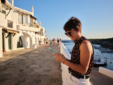 Woman smiling using smartphone in Binibeca Vell Menorca