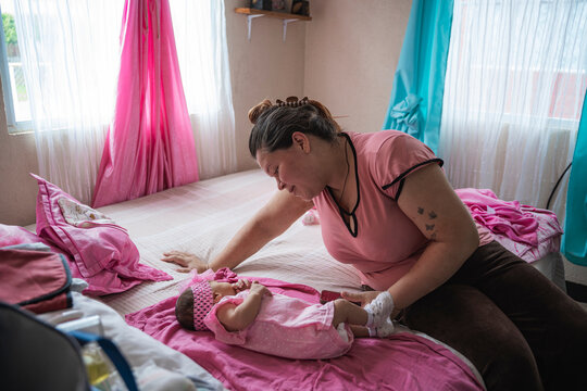 Parent showing affection to infant lying on bed