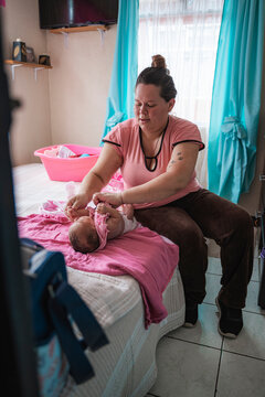 Mother changing clothes for newborn baby on bed