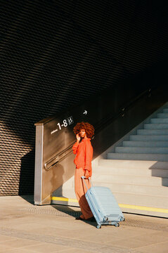 Travel film photo of a woman pulling a suitcase through a station