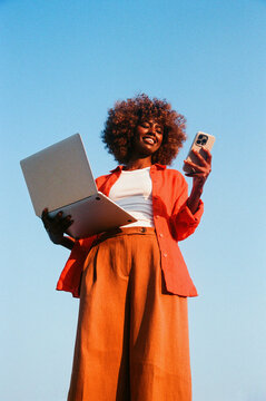 Woman holds laptop and smartphone blue sky film photo